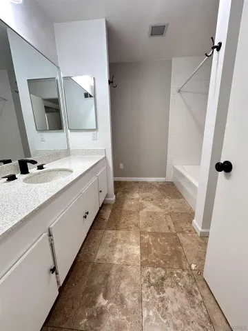 a bathroom with a granite countertop sink a mirror and shower