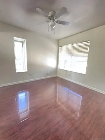 a view of an empty room with a window and wooden floor