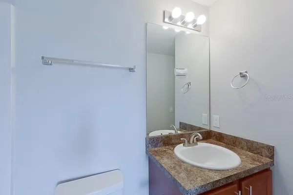 a bathroom with a granite countertop sink toilet a mirror and vanity