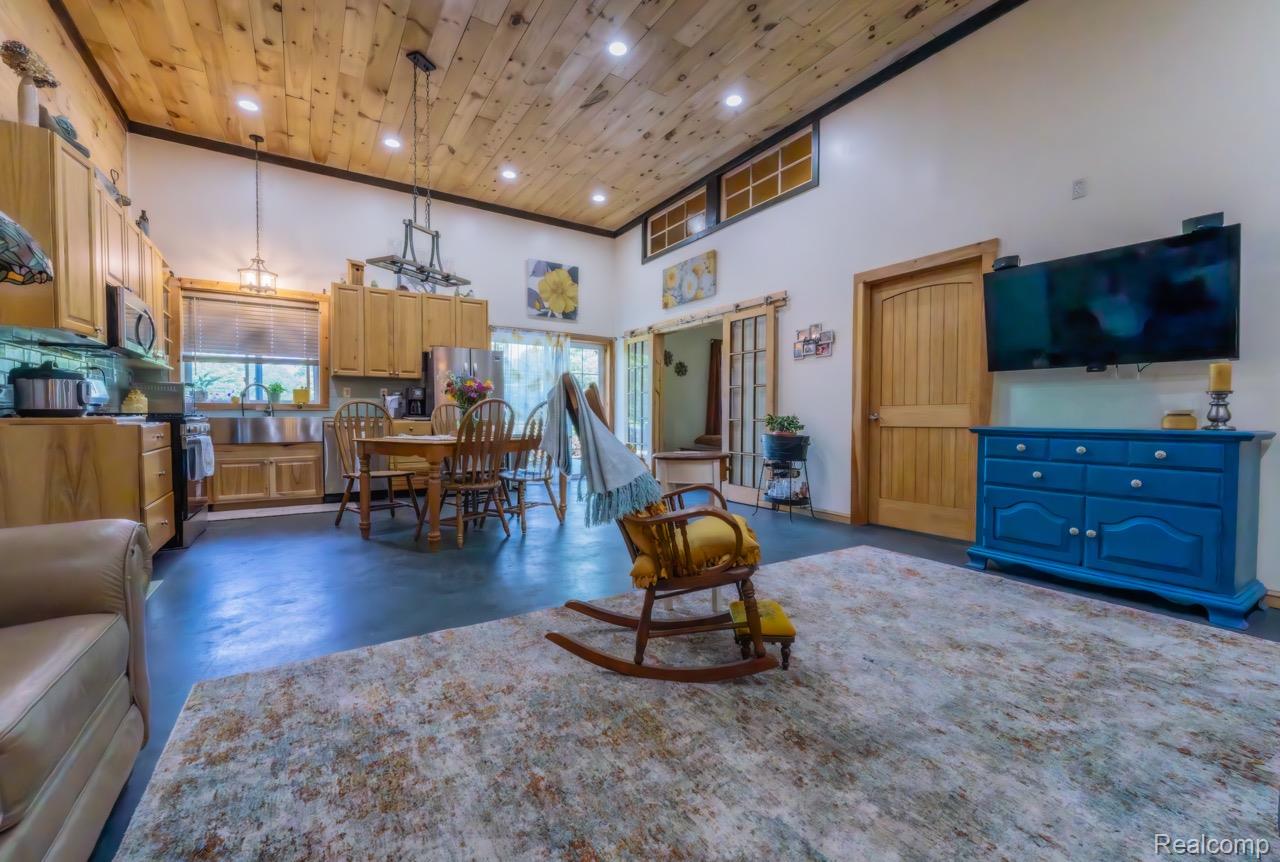 2418 South 41st Road South Cadillac, MI 49601 - Photo 11 of 57 Open-concept living space featuring a vaulted wood-plank ceiling, exposed wood beams, and clerestory windows