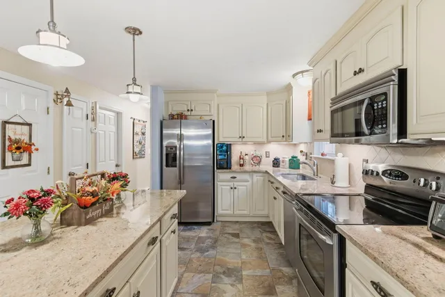 a kitchen with granite countertop a sink stainless steel appliances and cabinets
