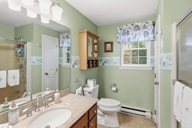 a bathroom with a granite countertop toilet a sink a mirror and a shower