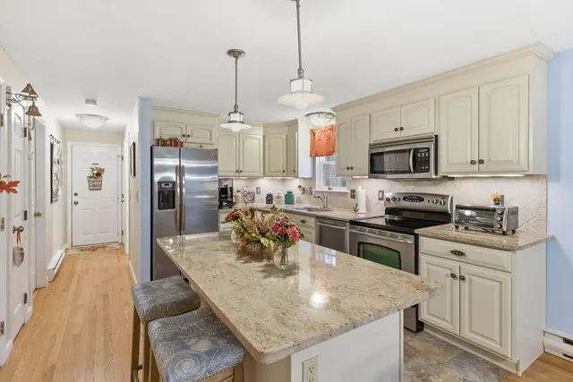 a kitchen with stainless steel appliances granite countertop a sink a stove a refrigerator a center island and cabinets