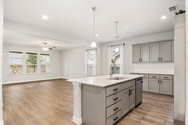 a kitchen with a sink chandelier and wooden floor