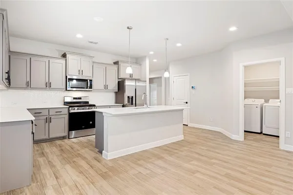 a large white kitchen with kitchen island a sink a stove a oven a counter space and cabinets