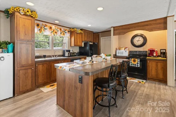 a kitchen with stainless steel appliances granite countertop a stove a refrigerator a microwave oven with a dining table and chairs with wooden floor