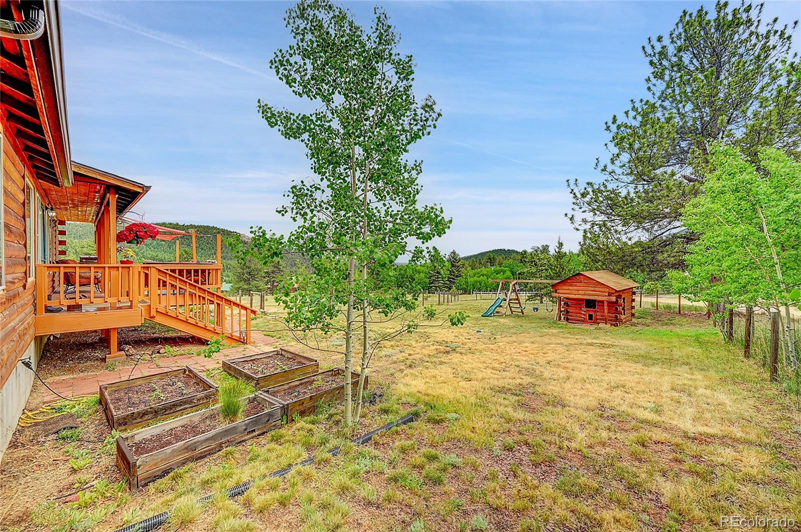 174 Saddlestring Road Bailey, CO 80421 - Photo 14 of 15 a backyard of a house with table and chairs plants and large trees