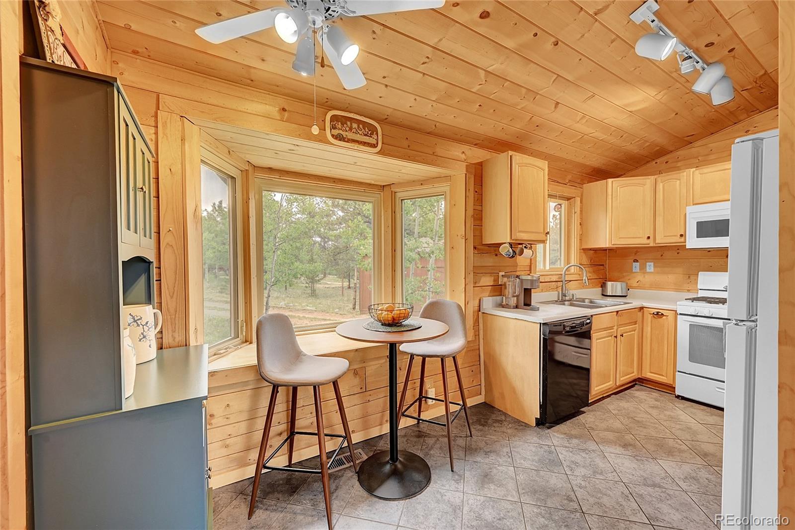 174 Saddlestring Road Bailey, CO 80421 - Photo 6 of 15 a kitchen with a table chairs stove and white cabinets