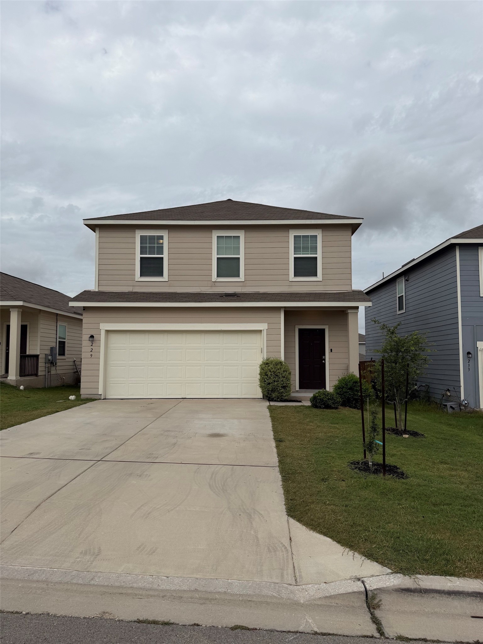 229-1 Night Riders Way Jarrell, TX 76537 - Photo 2 of 21 A well-maintained facade with a prominent two-car garage and a small lawn welcomes residents.