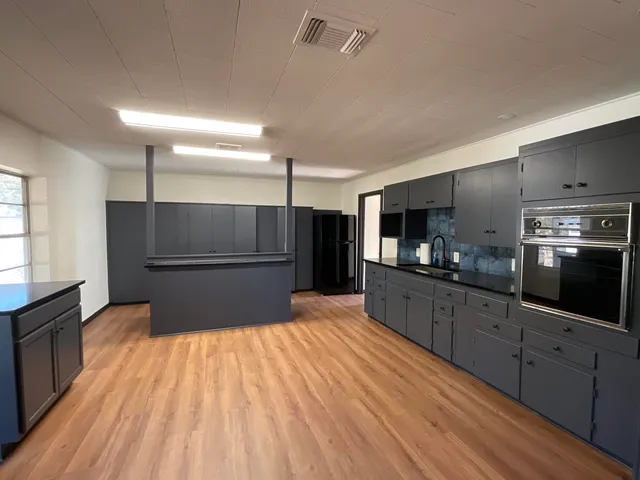 a large kitchen with stainless steel appliances wooden floor and a large window