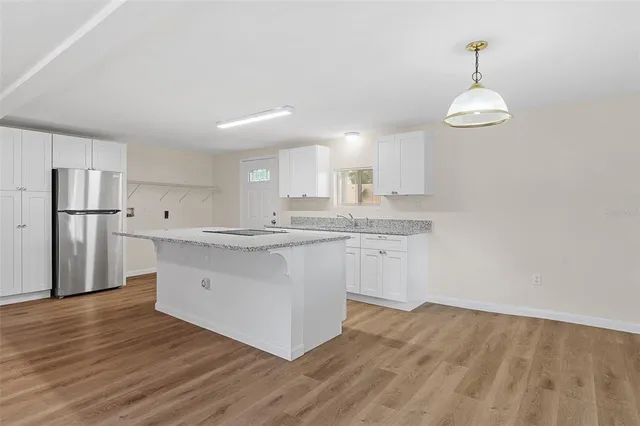 a kitchen with stainless steel appliances granite countertop a white cabinets a sink dishwasher and a stove with wooden floors