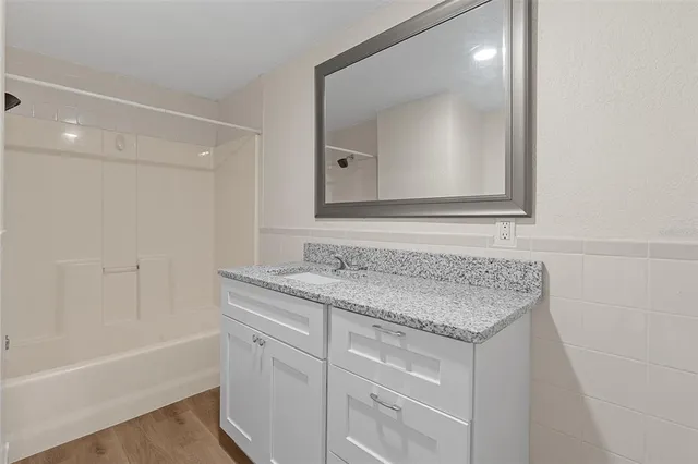 a bathroom with a granite countertop sink mirror and a bathtub