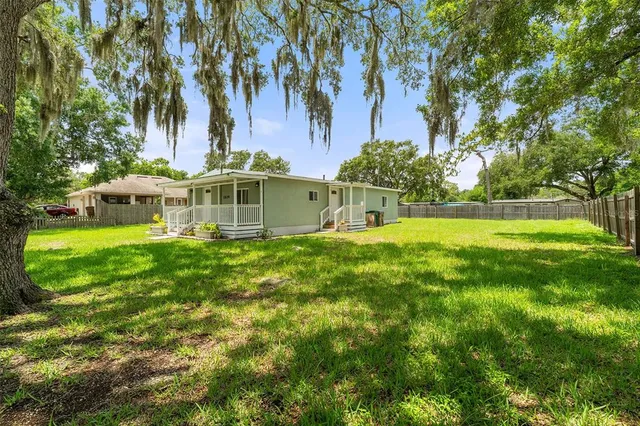 a view of a house with a big yard and palm trees
