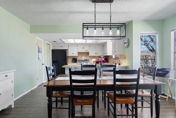 a kitchen with stainless steel appliances a white refrigerator a sink a stove and chairs with wooden floor