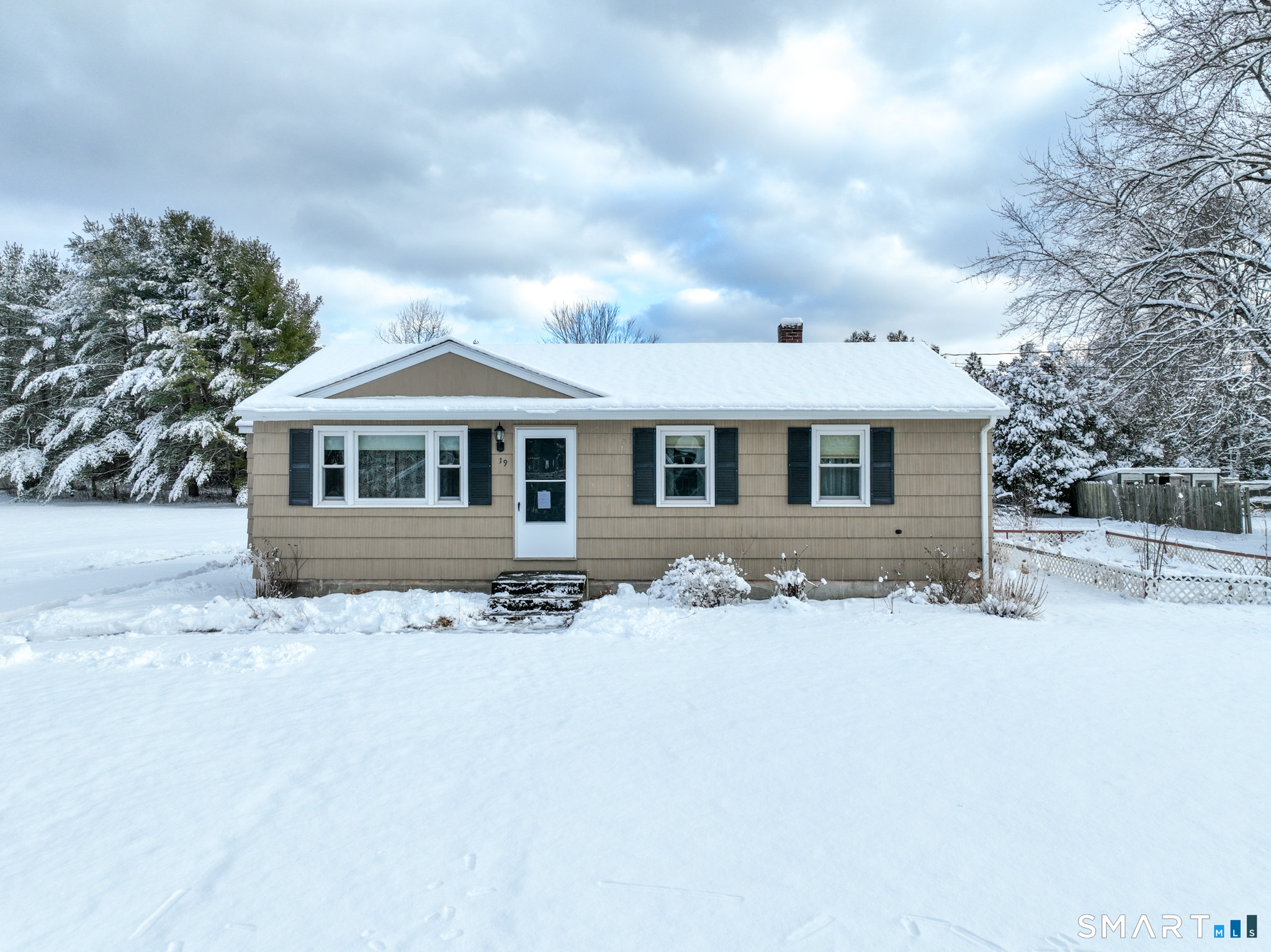 a front view of a house with a yard covered in snow