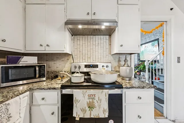 a kitchen with kitchen island granite countertop a stove and a white cabinets