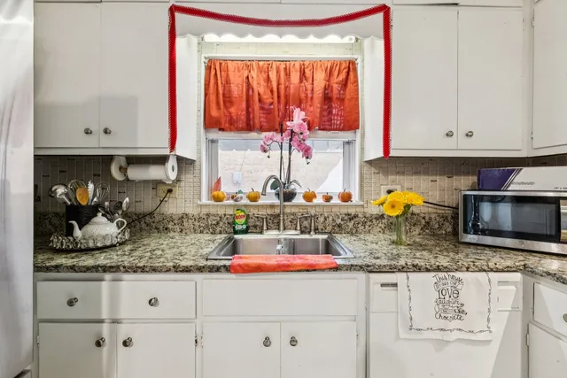 a kitchen with granite countertop white cabinets and window
