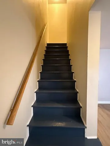 an empty room with a chandelier fan and wooden floor