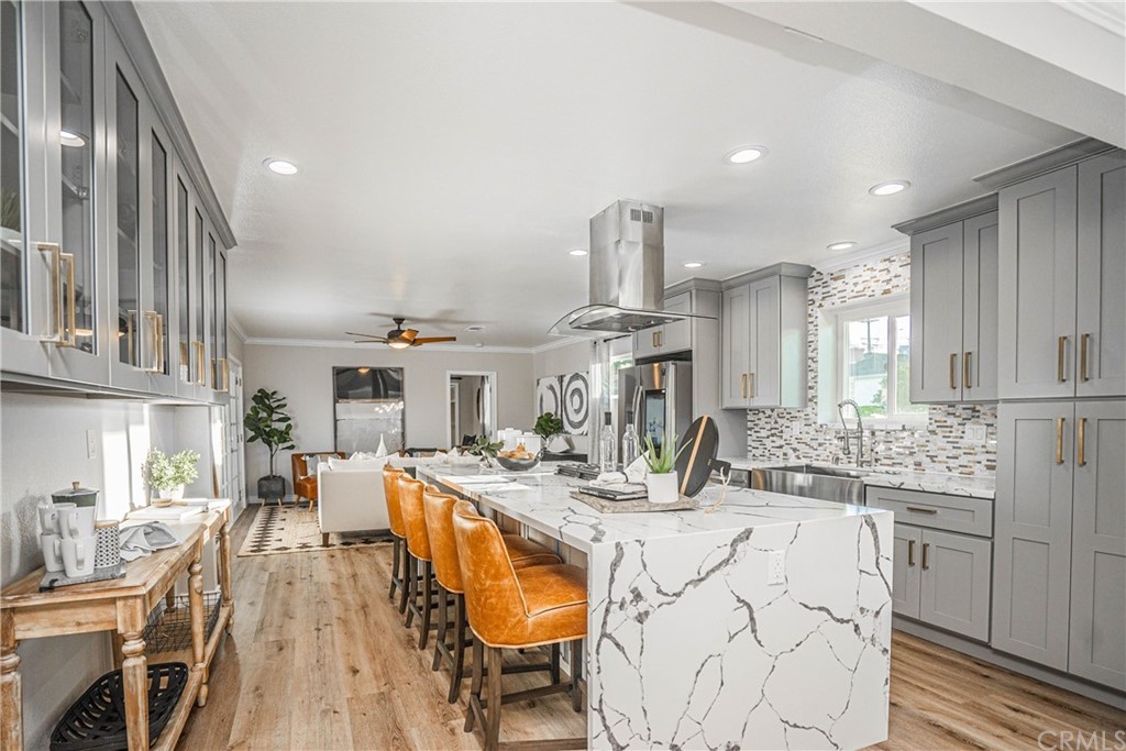 a kitchen with stainless steel appliances kitchen island granite countertop a sink dishwasher a stove a dining table and chairs with wooden floor