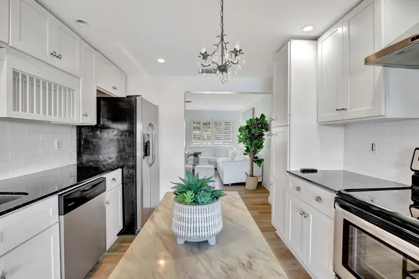 a kitchen with kitchen island white cabinets and stainless steel appliances