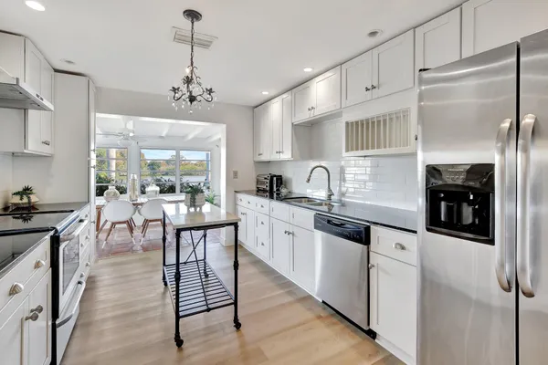 a kitchen with stainless steel appliances granite countertop a stove a sink a refrigerator a center island and a window