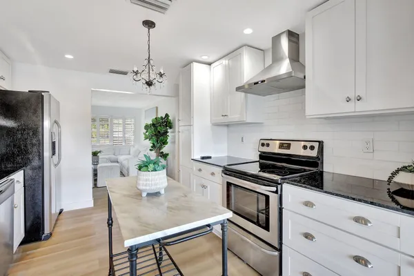 a kitchen with stainless steel appliances a kitchen island hardwood floor sink and stove
