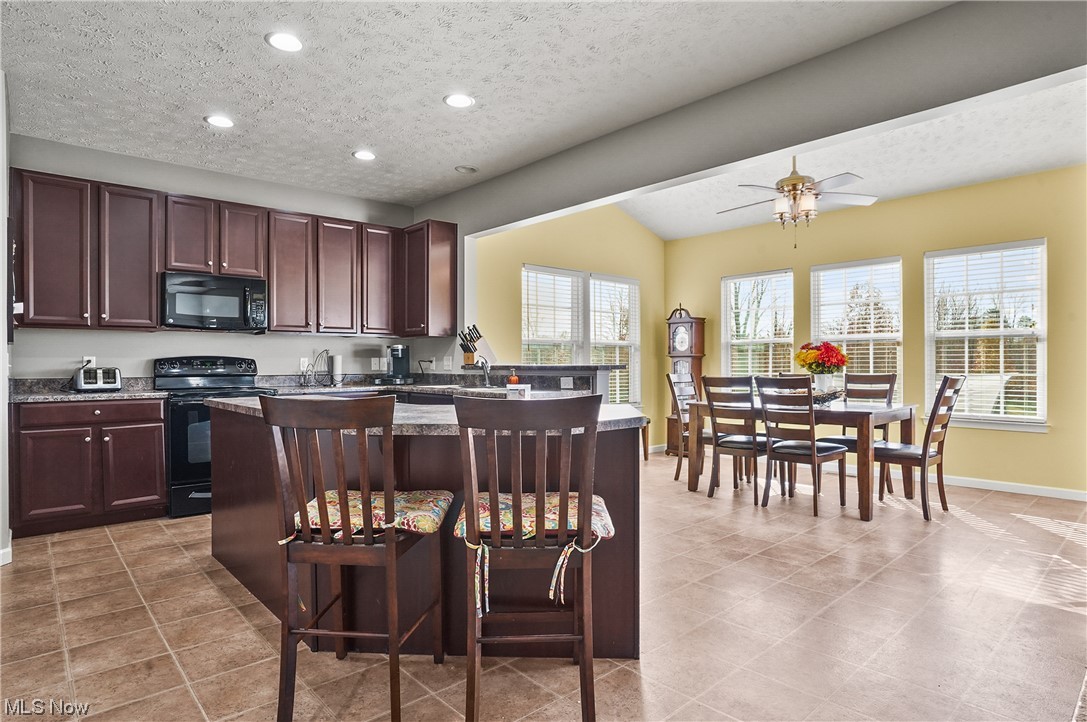 4169 Whitestone Road Kent, OH 44240 - Photo 11 of 33 Kitchen with a textured ceiling, light tile flooring, a breakfast bar, ceiling fan, and black appliances