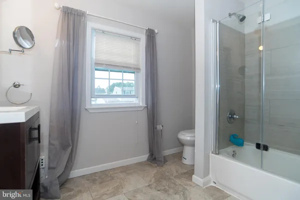 a bathroom with a granite countertop sink a toilet and shower
