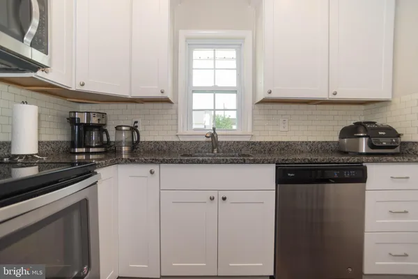 a kitchen with granite countertop white cabinets and a stove