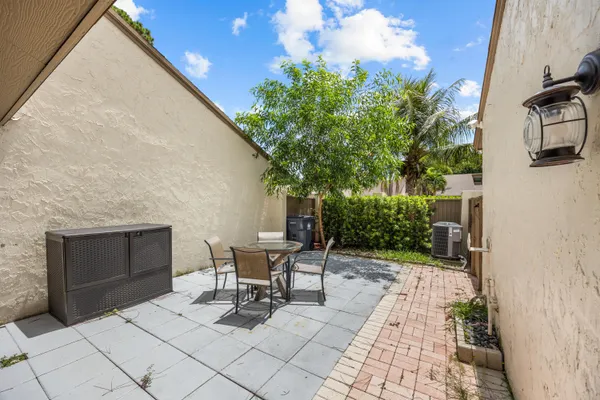 a patio with table and chairs and potted plants