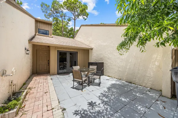 a patio with table and chairs and potted plants