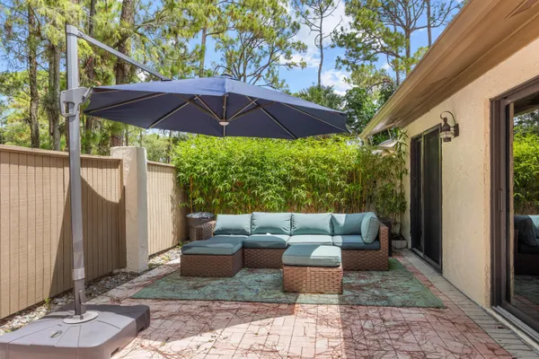 a view of a patio with couches table and chairs under an umbrella