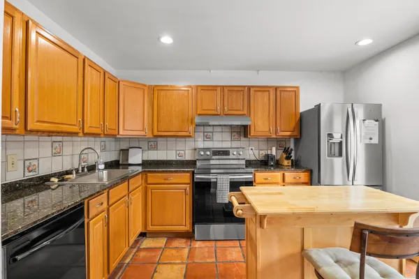 a kitchen with stainless steel appliances granite countertop a stove a sink dishwasher a refrigerator and cabinets with wooden floor