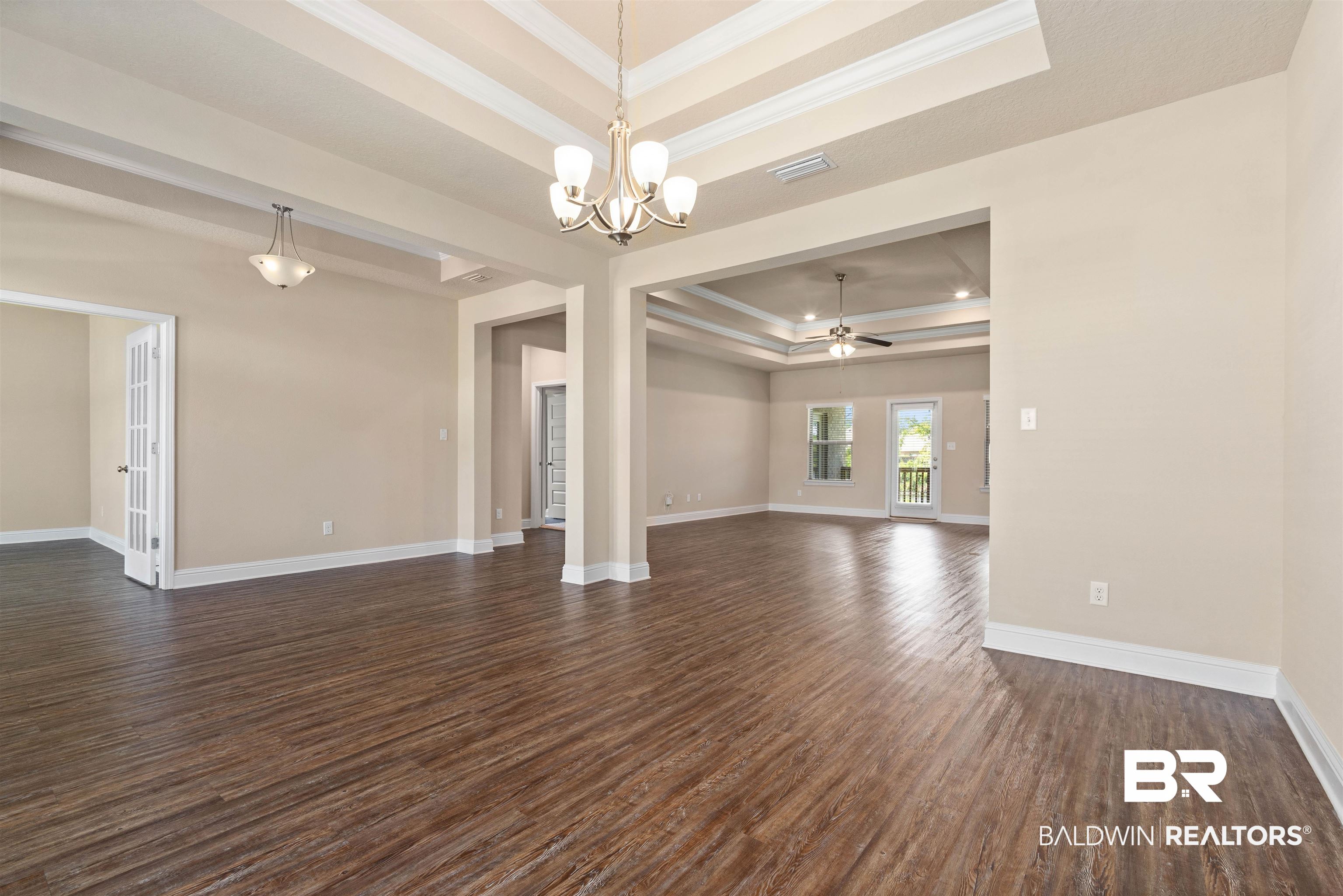 1864 Gwin Court Mobile, AL 36695 - Photo 17 of 37 Unfurnished living room featuring ceiling fan with notable chandelier, a raised ceiling, crown molding, and dark hardwood / wood-style flooring