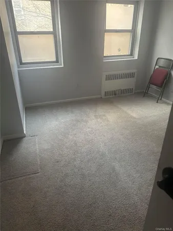 an empty room with a chair and windows