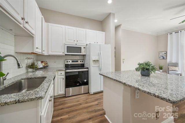 a kitchen with granite countertop a sink a stove and refrigerator