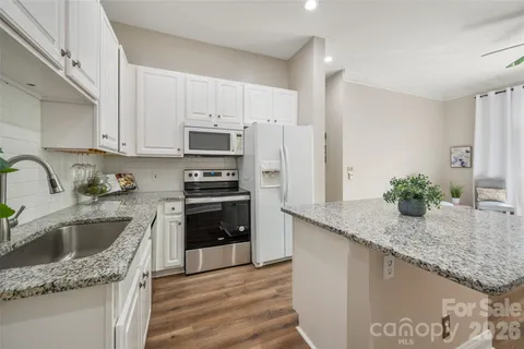 a kitchen with granite countertop a sink a stove and refrigerator