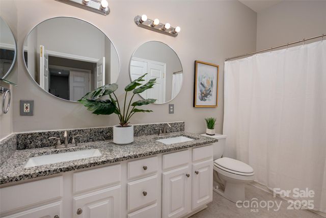 a bathroom with a granite countertop toilet a sink and mirror