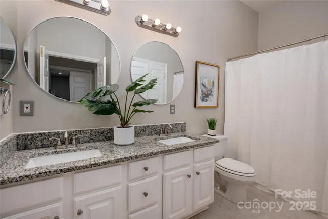 a bathroom with a granite countertop toilet a sink and mirror