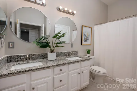 a bathroom with a granite countertop toilet sink and mirror