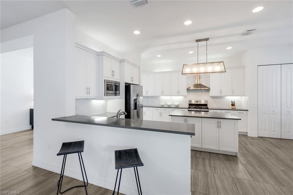 4549 Azalea Drive Naples, FL 34119 - Photo 13 of 49 a kitchen with stainless steel appliances a sink a stove a refrigerator and white cabinets