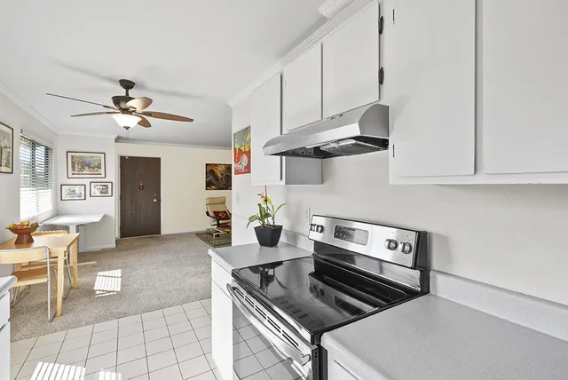 a kitchen with stainless steel appliances granite countertop a stove white cabinets a dining table and chairs