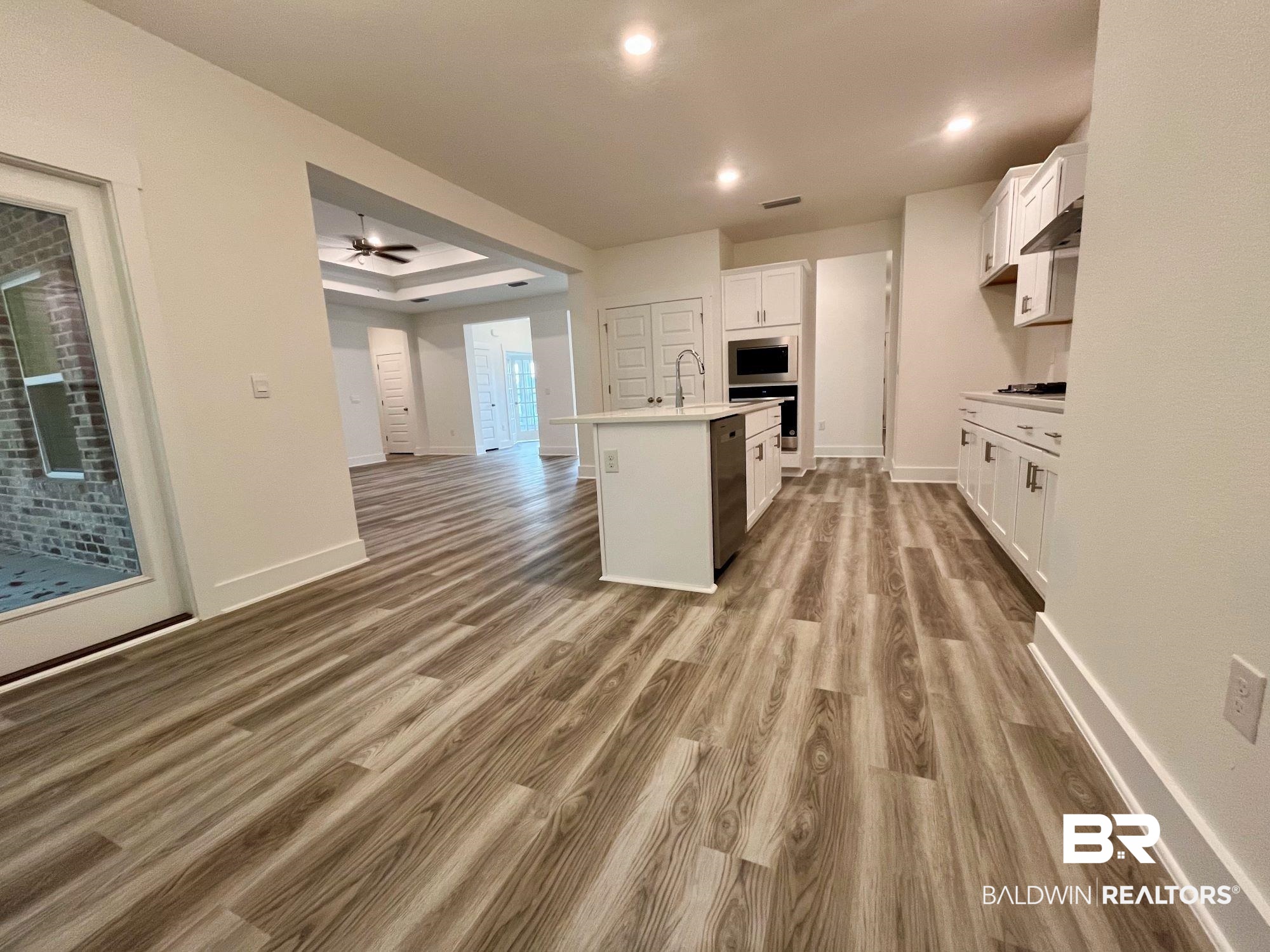 334 Barndling Street Fairhope, AL 36532 - Photo 17 of 34 Kitchen featuring wood-type flooring, white cabinets, stainless steel microwave, ceiling fan, and a kitchen island with sink