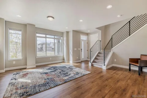 a view of an empty room with stairs wooden floor and a window