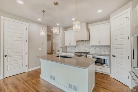 a kitchen with kitchen island a sink a stove a refrigerator and white cabinets