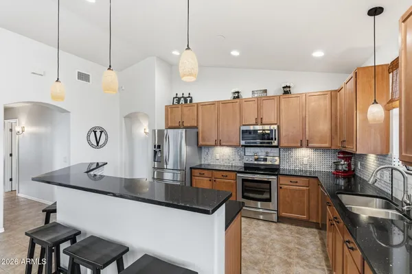 a open kitchen with stainless steel appliances granite countertop a sink dishwasher a refrigerator and a dining table with wooden floor
