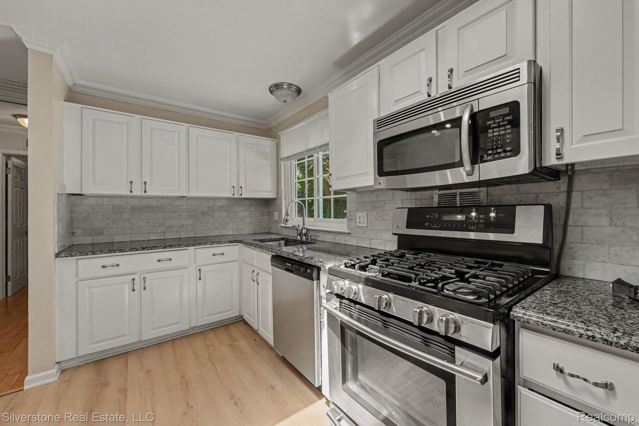 547 Reed Street Northville, MI 48167 - Photo 10 of 38 Kitchen featuring white cabinetry, granite countertops, tile backsplash, stainless steel appliances, and wood-finish flooring