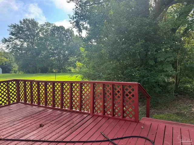 a view of a wooden deck and a yard with a large tree
