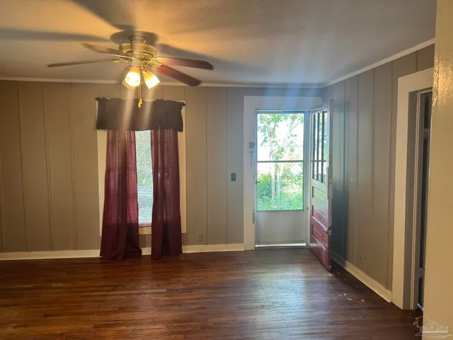 an empty room with wooden floor and windows