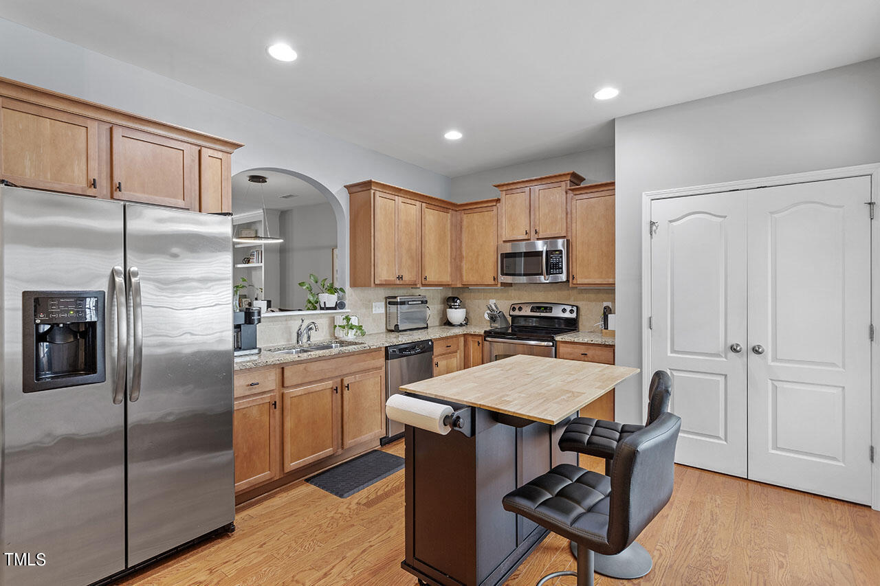 1329 Still Monument Way Raleigh, NC 27603 - Photo 18 of 42 a kitchen with granite countertop a refrigerator a stove a sink a dining table and chairs